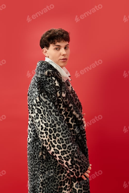 Preview: Stylish man in a bold leopard print coat poses confidently against a vibrant red backdrop