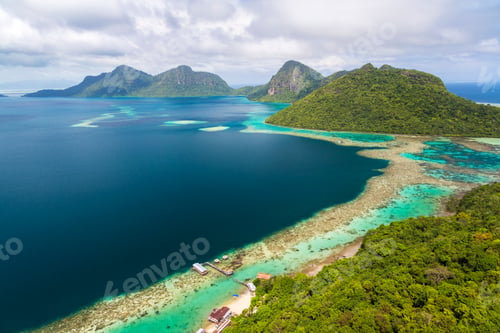 Preview: High angle view along coastline of tropical island, mountains in the distance.