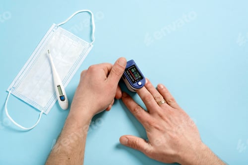 Preview: Human male hands pulse oximeter used to measure pulse rate and oxygen levels with medical blue