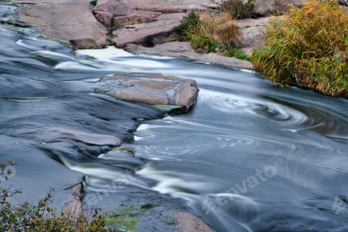 Preview: Stream runs among white wet stones covered with grass in golden autumn