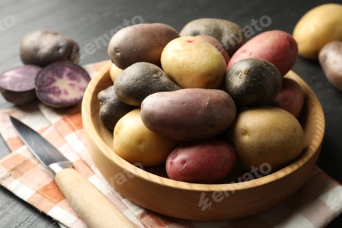 Preview: Different types of potatoes in bowl and knife on black table, closeup