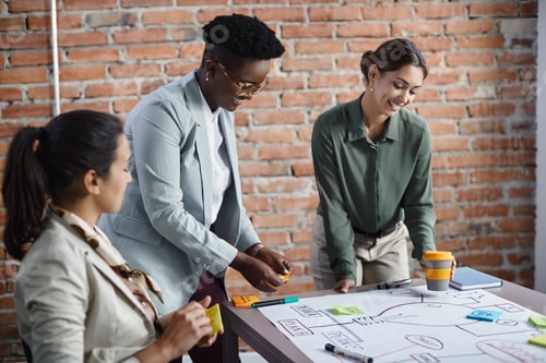 Preview: Team of happy female entrepreneurs brainstorming while making mind map during meeting in office.