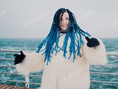 Preview: Beautiful young hipster woman with blue African braids in winter near sea