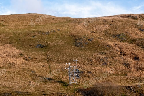 Preview: Picturesque view of a grassy hillside with a tall telephone tower in the foreground