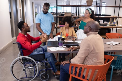 Preview: Disabled young african american businessman discussing with biracial colleagues in meeting
