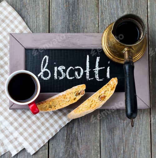 Preview: Homemade biscotti with nuts and a cup of coffee on the old wooden table background. Selective focus.