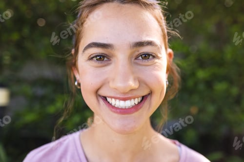 Preview: Portrait of happy biracial woman with long brown hair smiling in sunny garden