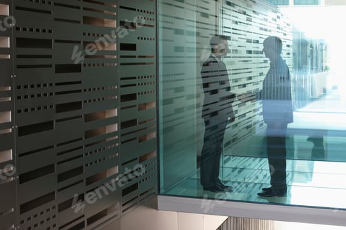 Preview: Germany, Cologne, Businessmen shaking hands behind glass door