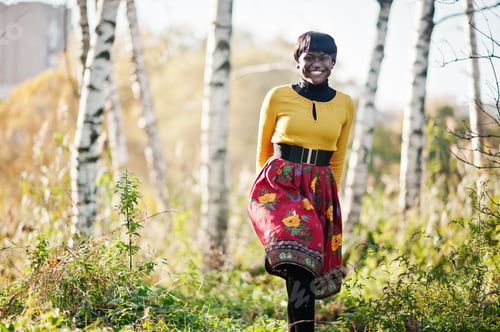 Preview: African american girl at yellow and red dress at golden autumn fall park.