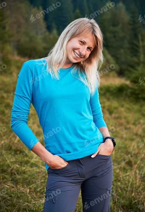 Preview: Young joyful woman standing outdoors in meadow.