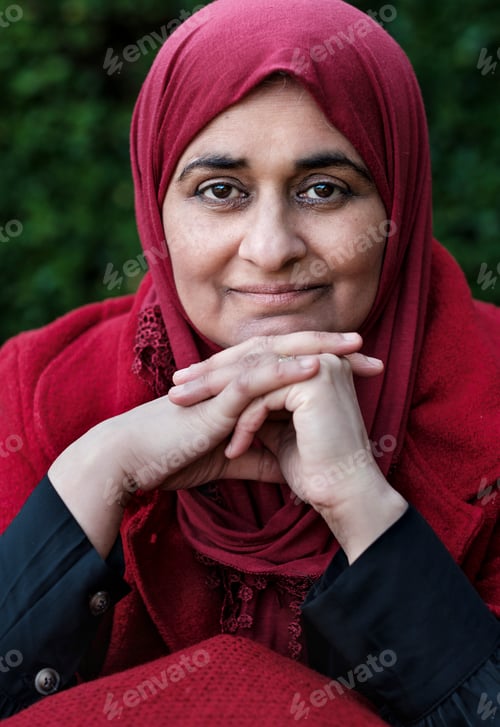 Preview: Muslim mature woman wearing hijab posing smiling in a red outfit.