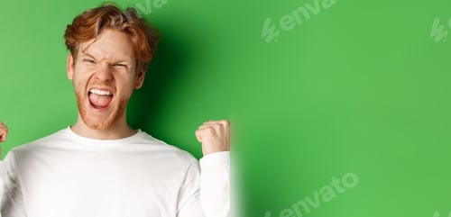Preview: Close-up of lucky young man winner, celebrating victory, shouting yes with joy and making fist