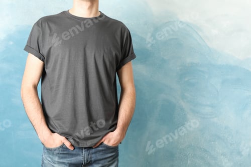 Preview: Men in blank grey t-shirt against blue background, space for text