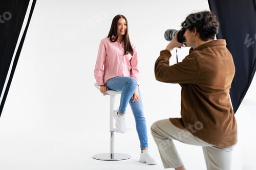 Preview: Stylish photoshoot. Male fashion photographer taking picture of young european woman in casual wear