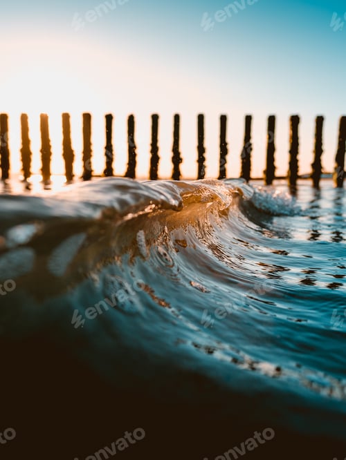 Preview: Vertical closeup shot of an ocean wave with some logs of wood in the background
