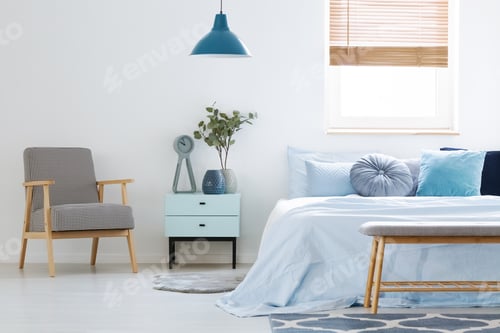 Preview: Plant on cabinet between patterned armchair and blue bed in bedr