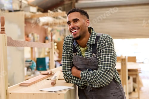 Preview: Portrait Of Male Apprentice Working As Carpenter In Furniture Workshop