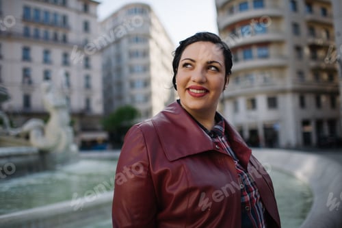 Preview: Plus size Young woman wearing red leather jacket looking up while smiling