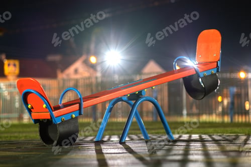 Preview: Seesaw swing in preschool yard with soft rubber flooring at night.