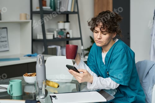 Preview: Female Healthcare Worker Checking Smartphone During Break