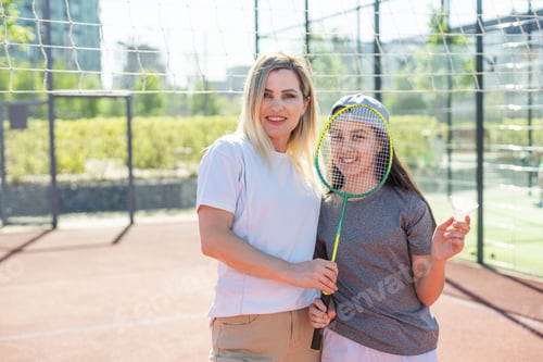 Preview: Mother and daughter are playing badminton outside in the yard on summer hot day