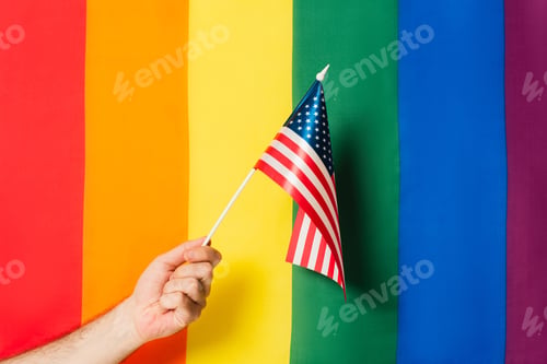 Preview: cropped view of man holding flag of america against lgbt colorful background