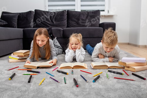 Preview: Group of children are reading books and drawing with pencils while lying on floor. Concept of family
