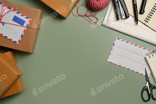 Preview: Top view of gift boxes, clews of rope, correspondence envelope and scissors on green background.