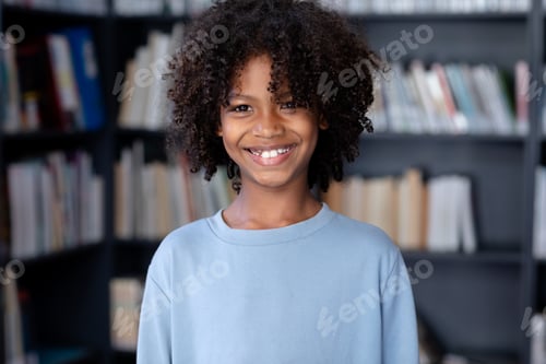 Preview: African american schoolboy wearing blue long sleeve t shirt with copyspace over library