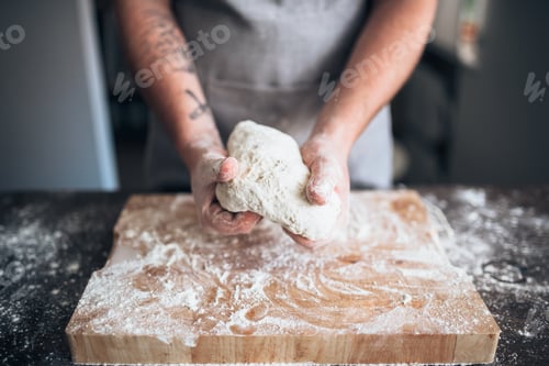 Preview: Male baker hands kneading dough on wooden table