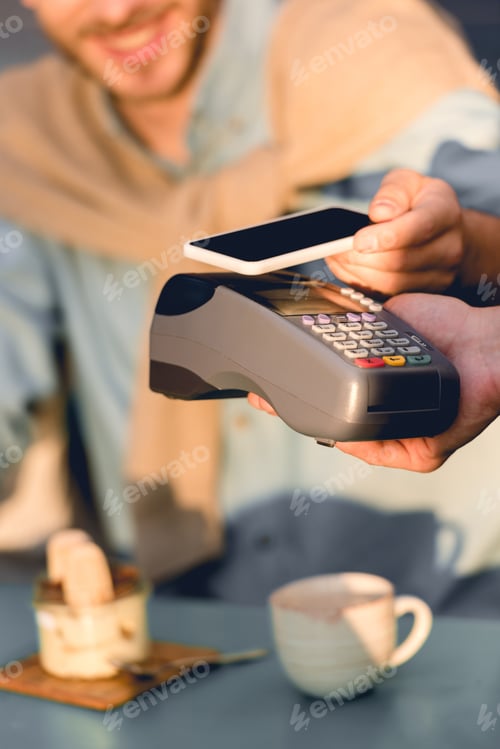 Preview: cropped view of man paying with smartphone in cafe