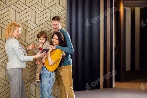 Preview: Saleswoman showing a young couple with a child the panels for decorating the interior of the home.