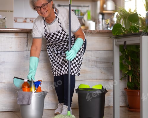 Preview: Smiling senior woman ready to start with housework. Holds a plastic bucket with items for cleaning