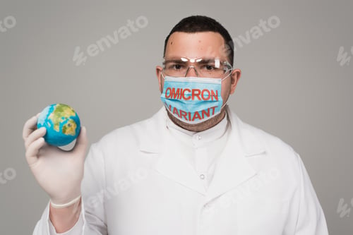 Preview: Scientist in medical mask with omicron variant holding small globe isolated on grey