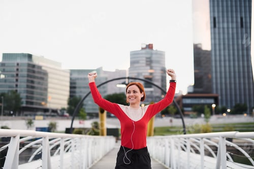 Preview: Front view of young woman runner with earphones in city, resting