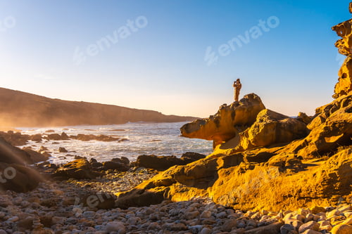 Preview: A young woman taking a photo at sunset in the stone cove on the Jaizkibel mountain