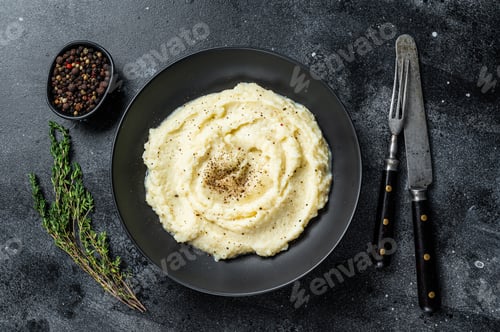 Preview: Potato puree, Mashed potatoes in a plate with herbs. Black background. Top view
