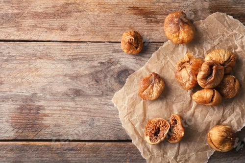Preview: Parchment with dried figs on wooden background, top view. Space for text