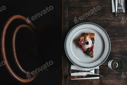 Preview: top view of delicious pizza slice on plate with setting and on rustic wooden table