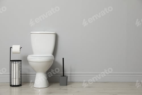 Preview: Ceramic toilet bowl, brush and paper near grey wall indoors. Space for text