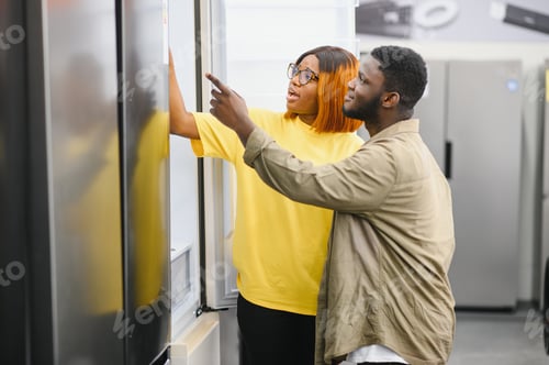 Preview: Young african american man and woman are choosing a fridge in an appliance store.