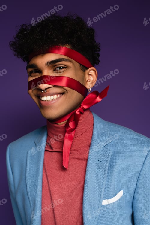 Preview: joyful african american man tied with red ribbon on purple