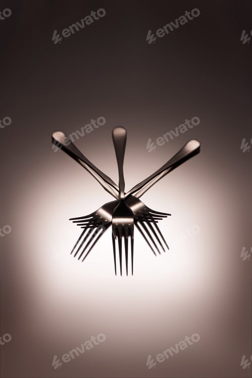 Preview: close-up view of shiny metal forks reflected on grey