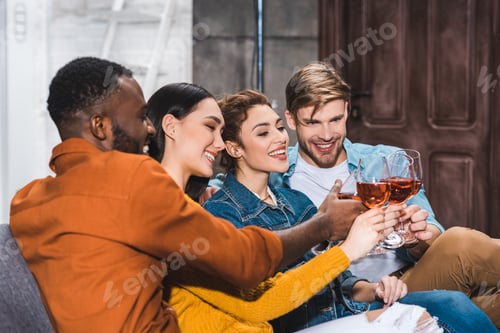 Preview: happy young multiethnic friends clinking wine glasses