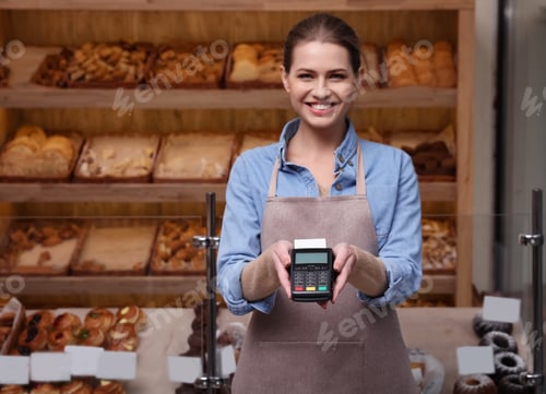 Preview: Seller holding payment terminal in bakery. Space for text