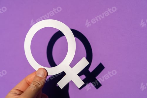 Preview: Closeup of a person holding the female symbol on a purple background