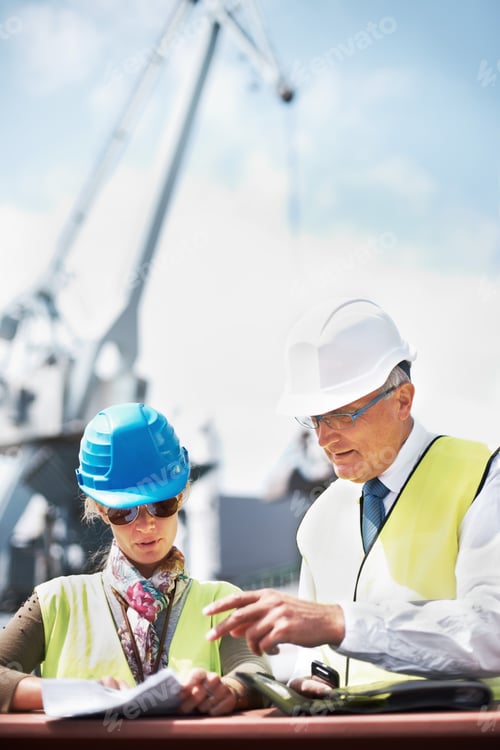 Preview: Two dock workers holding paperwork while standing in the shipyard