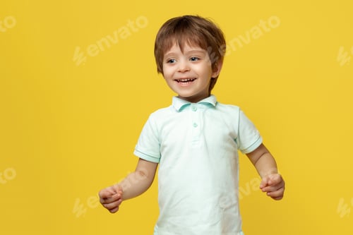 Preview: Adorable little kid in casual summer outfit with bright smile posing over yellow background.