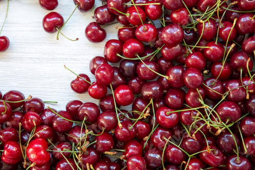 Preview: Fresh ripe cherries on a white wooden surface, top view. Flat-lay, overhead.