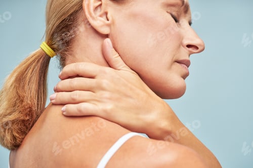 Preview: Suffering from back pain. Rear view of a mature woman touching her neck while standing
